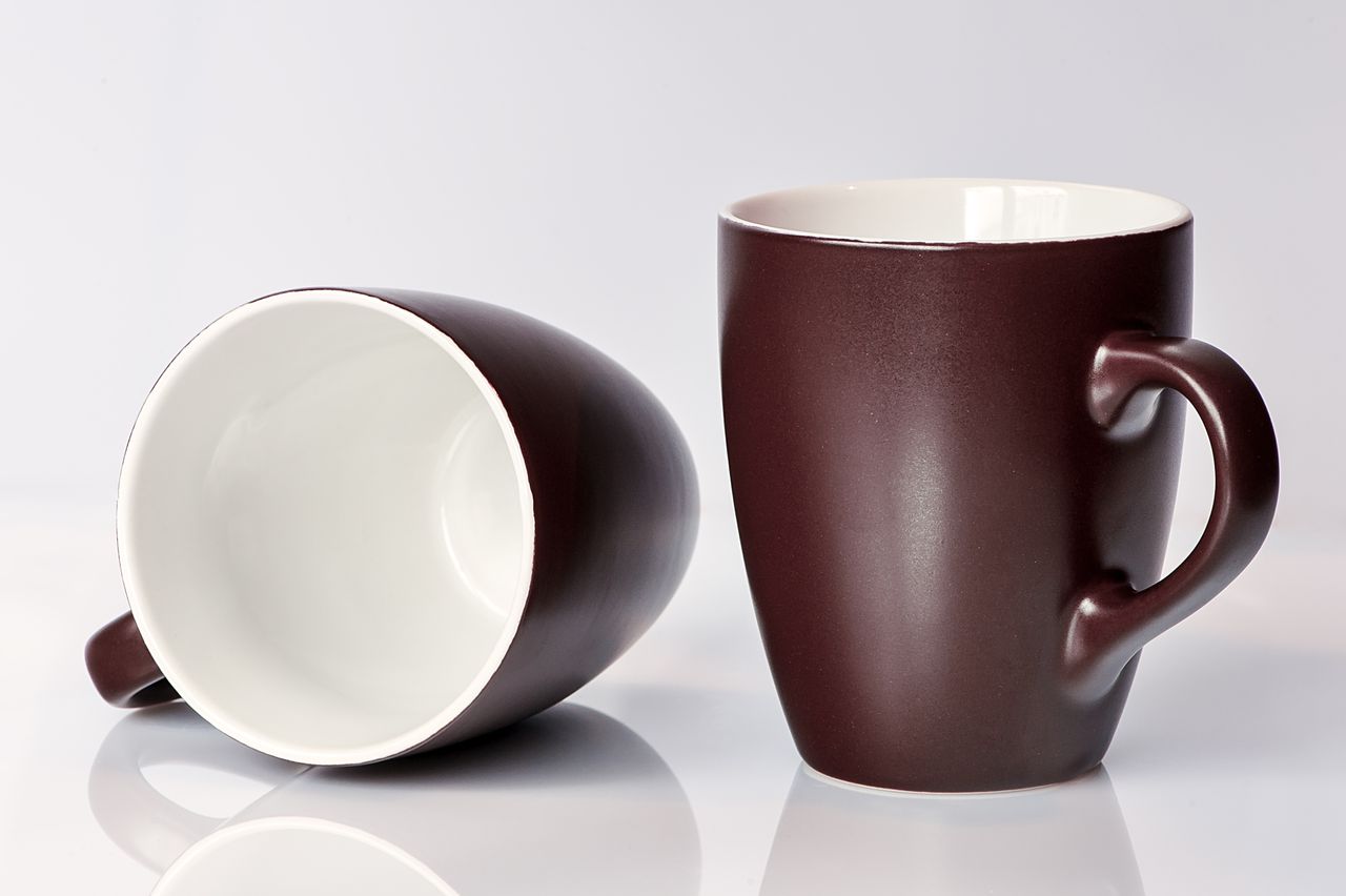 trusted-partner A pair of classic brown ceramic mugs displayed elegantly against a clean white backdrop, perfect for home and kitchen settings.
