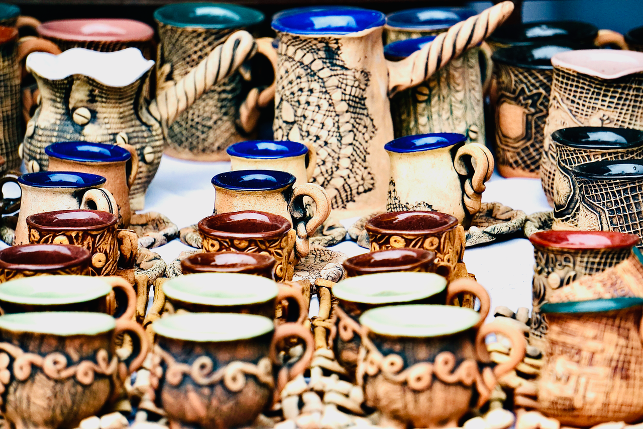 gallery-04 Intricately designed handcrafted ceramic mugs on display at a craft market stall.
